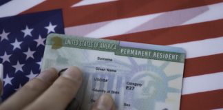 Permanent Resident Green card of United states of America on flag of USA. Above close up view.
