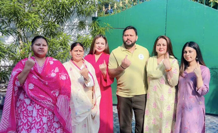 RJD leader Tejashwi Yadav poses for a picture with his family, showing their ink-marked fingers after casting their votes