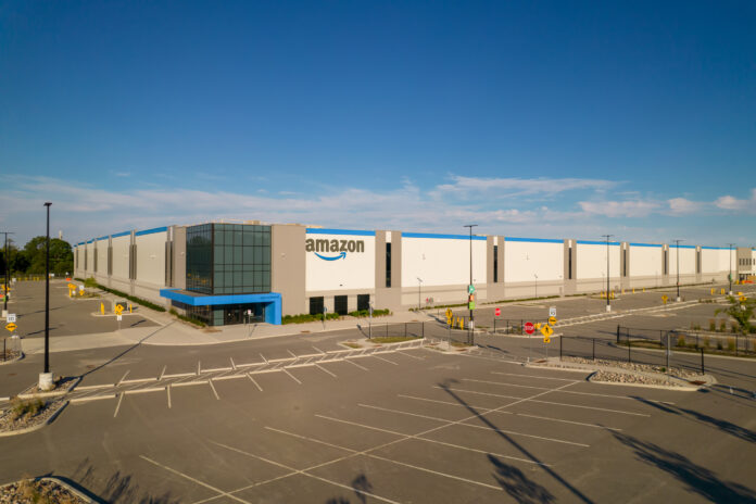 Aerial view of Amazon logo brand name and trademark at distribution center warehouse Entrance. Large storage facility and office headquarter.