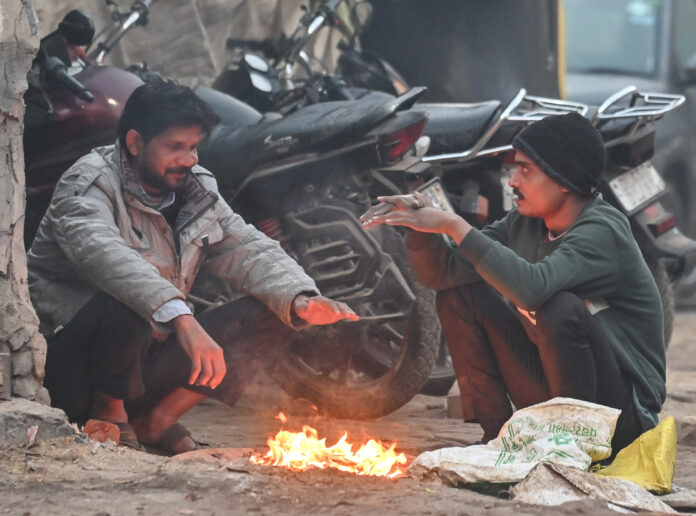 People sit around a bonfire to keep themselves warm on a cold winter morning