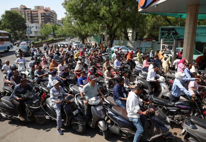 People queue to fill petrol in their two-wheelers, amid the ongoing U.S.-Israeli conflict with Iran, in Ahmedabad